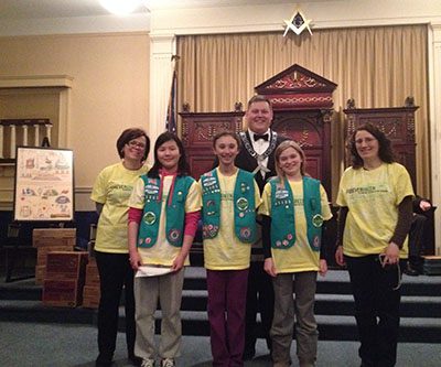 Wor. John Nichols poses with Girl Scout Troop 65305 who donated 150 boxes of cookies to the spouses of deployed airmen at Hanscom Air Force Base